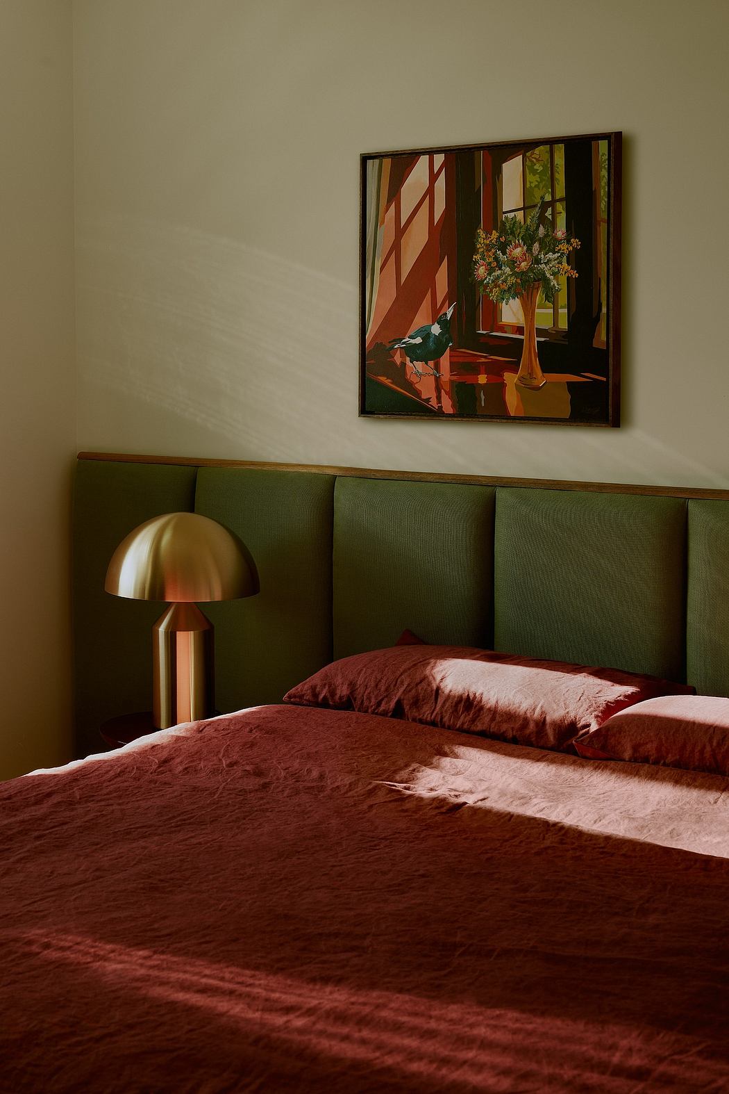 Cozy bedroom with minimalist decor, textured burgundy bedding, and a framed painting on the wall.