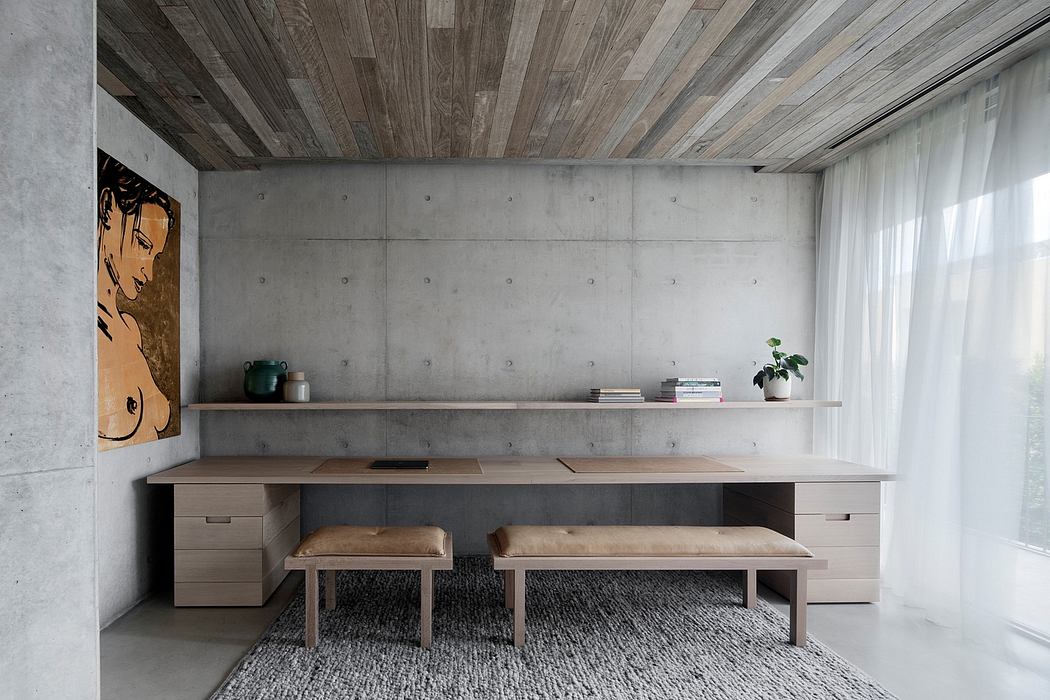 Minimalist workspace with concrete walls, wooden ceiling, and built-in shelving.