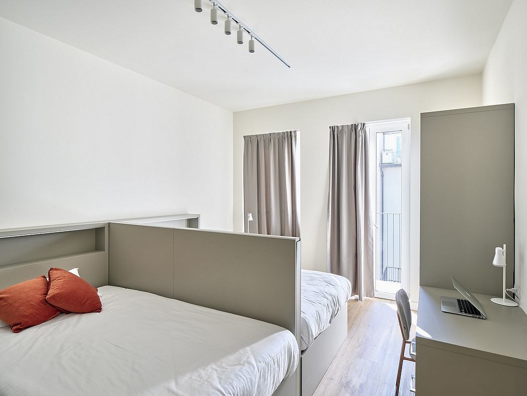 Modern, minimalist bedroom with white walls, wooden floors, and gray built-in furniture.