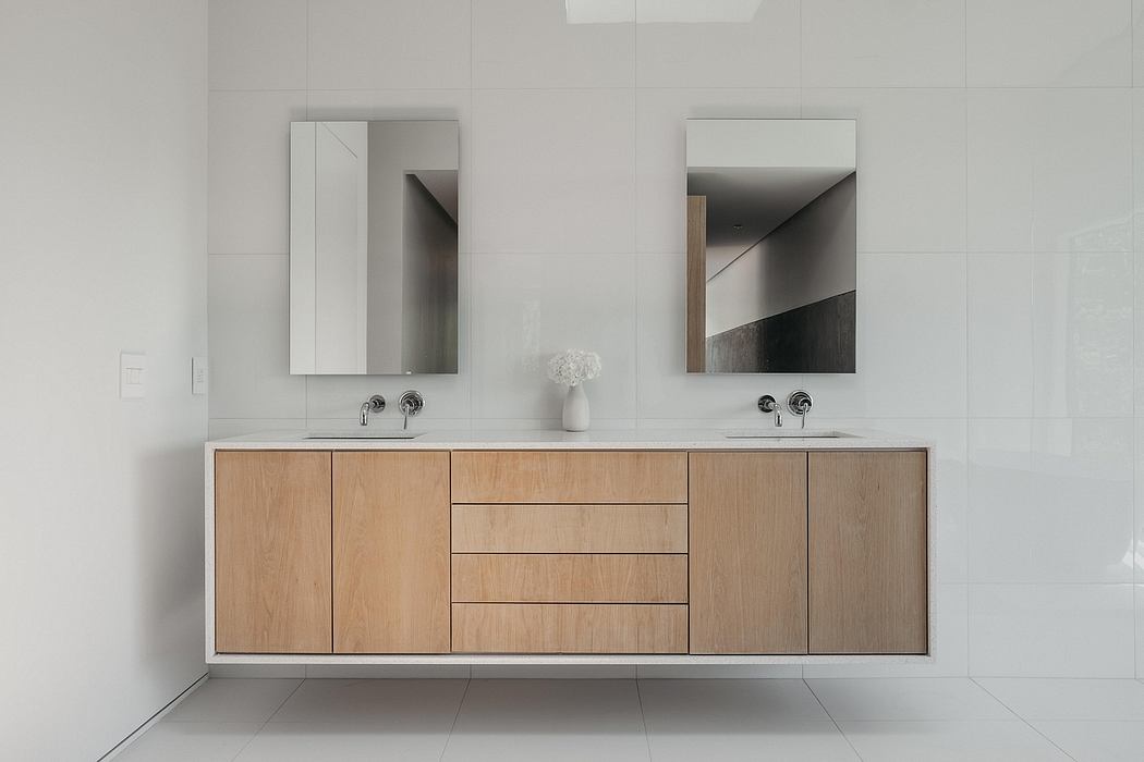 A modern, minimalist bathroom vanity with natural wood drawers and built-in mirrors.