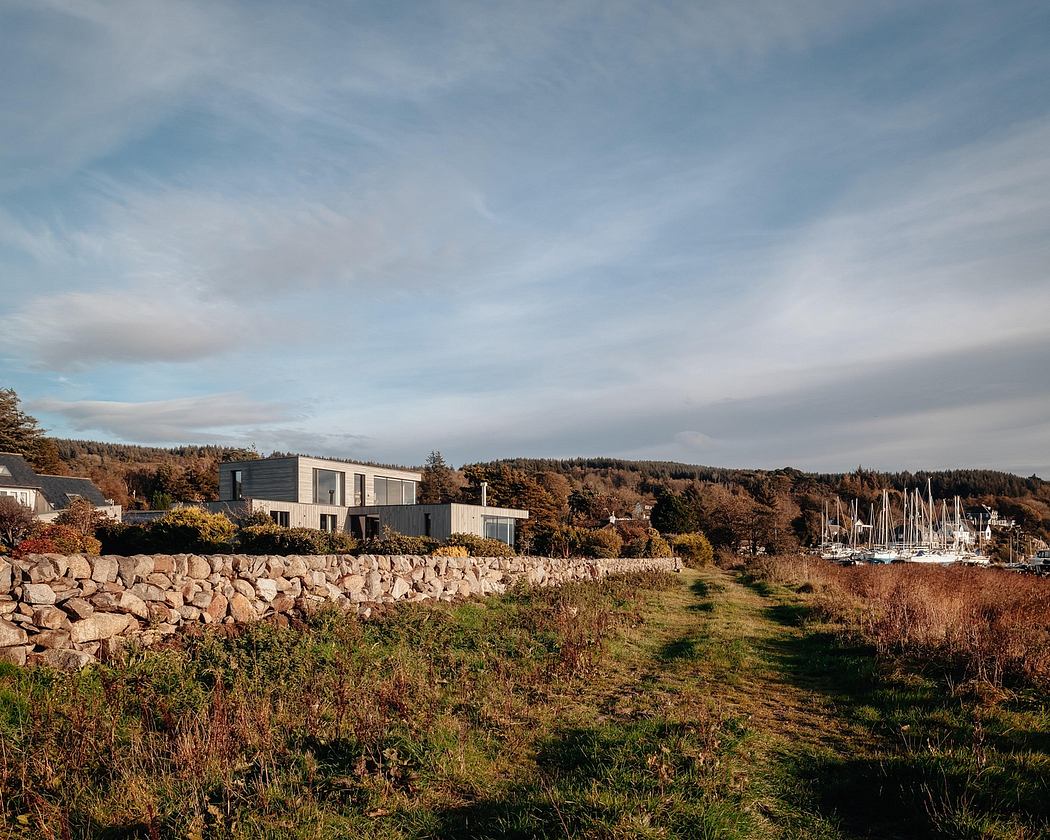 Modern waterfront homes with stone walls and wooded surroundings.