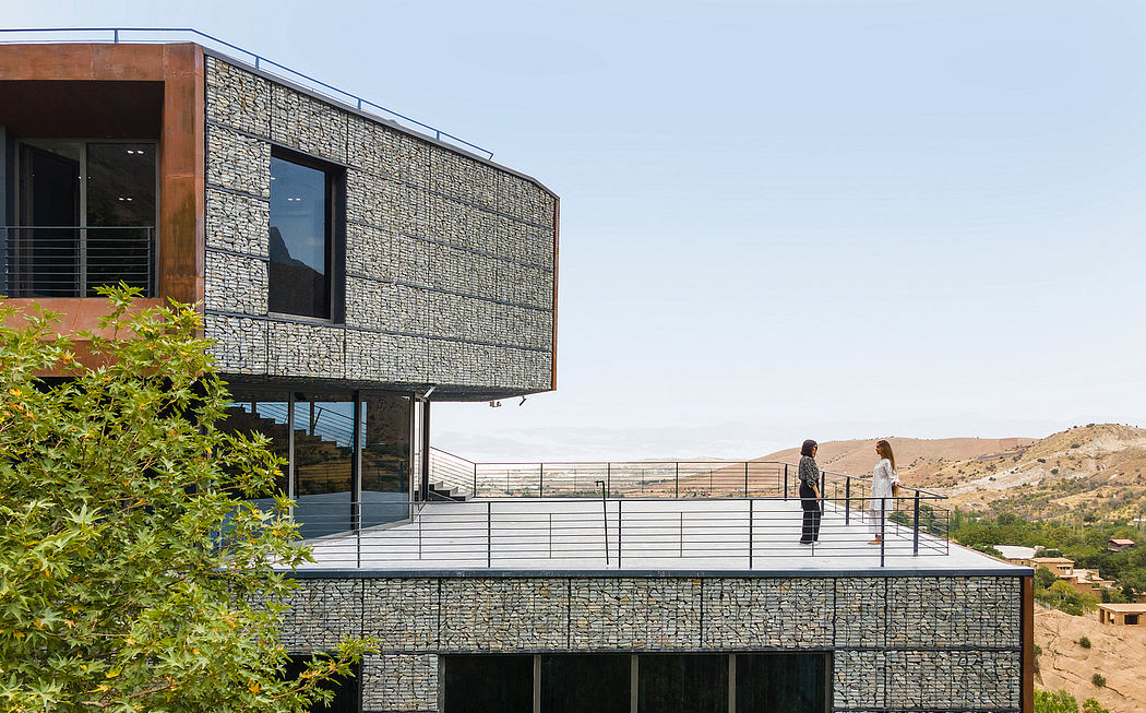 Modern, stone-clad building with cantilevered upper floor and expansive windows overlooking a desert landscape.