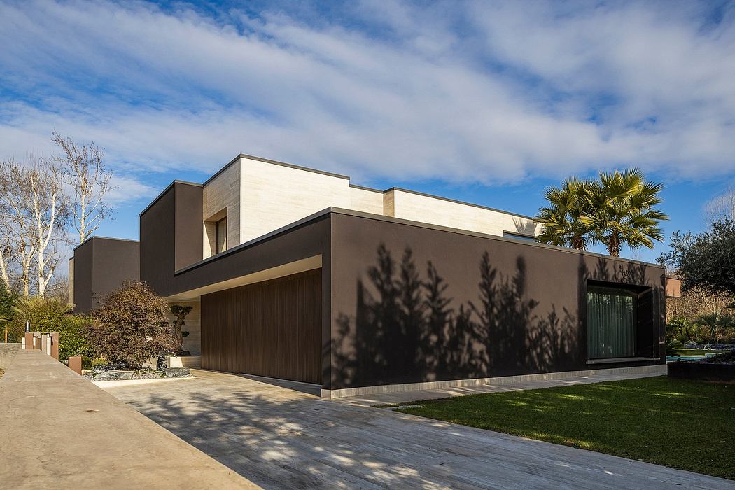 Modern house with sleek, geometric design, contrasting light and dark tones, and a palm tree accent.