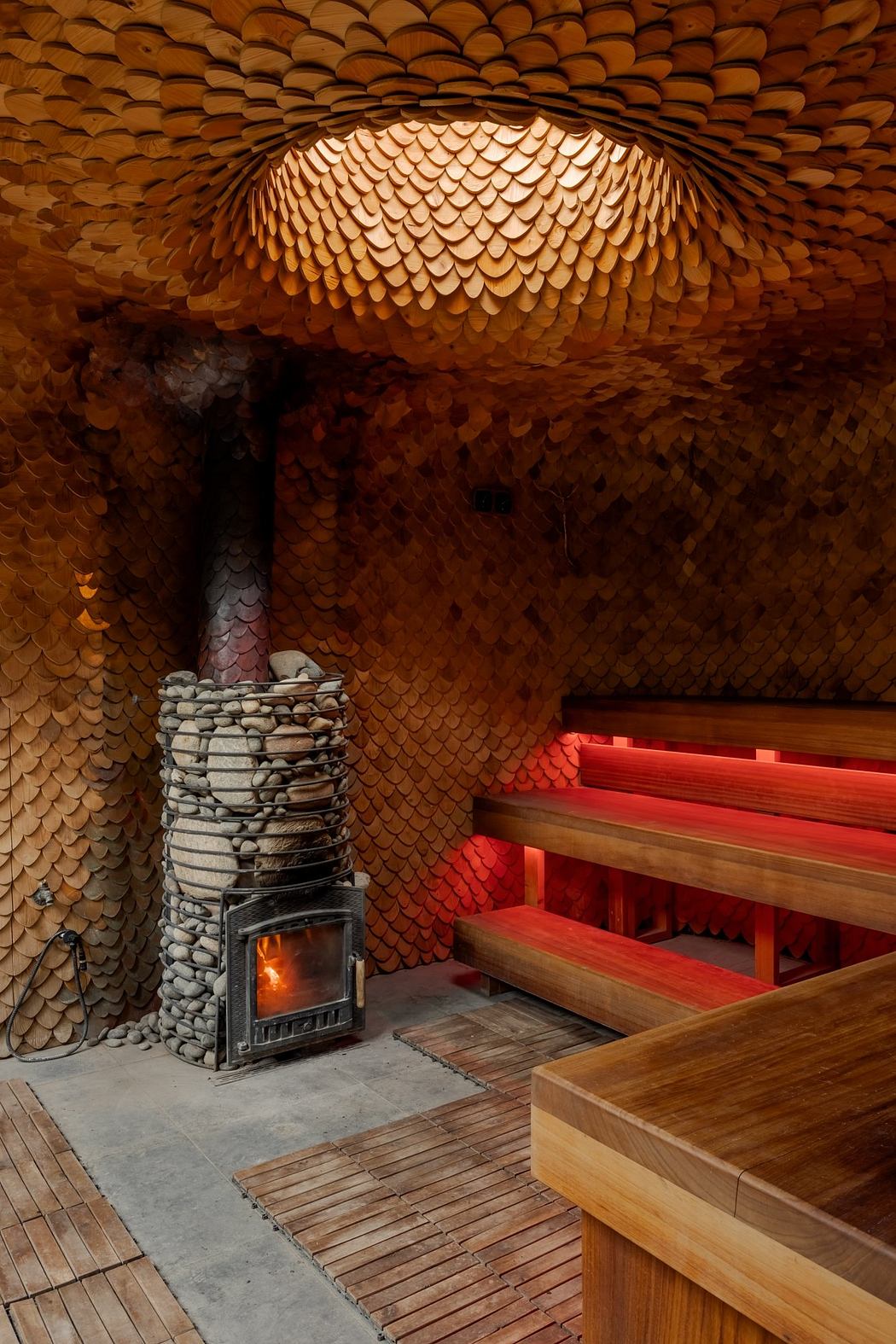 Intricate wooden scales form a dome over a cozy sauna with a stone fireplace.