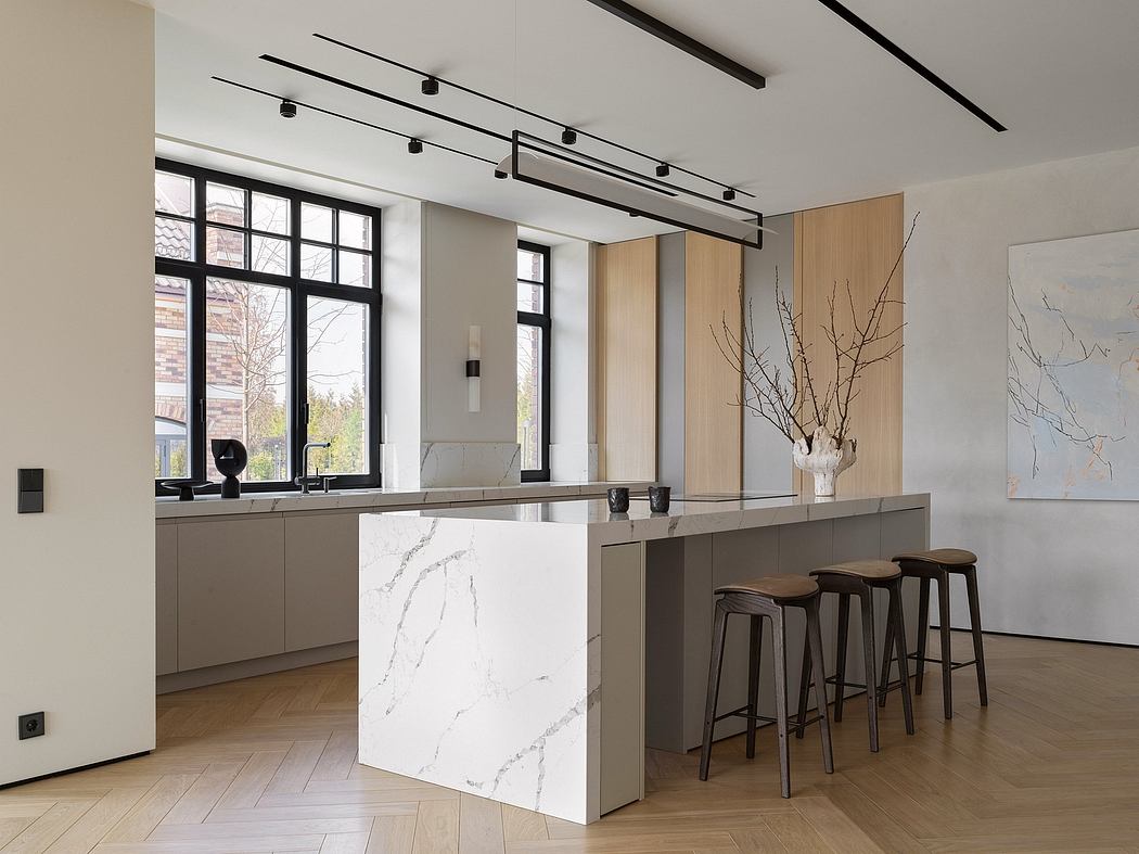 Modern kitchen with minimalist, industrial design. Marble-topped island, track lighting, and wood flooring.