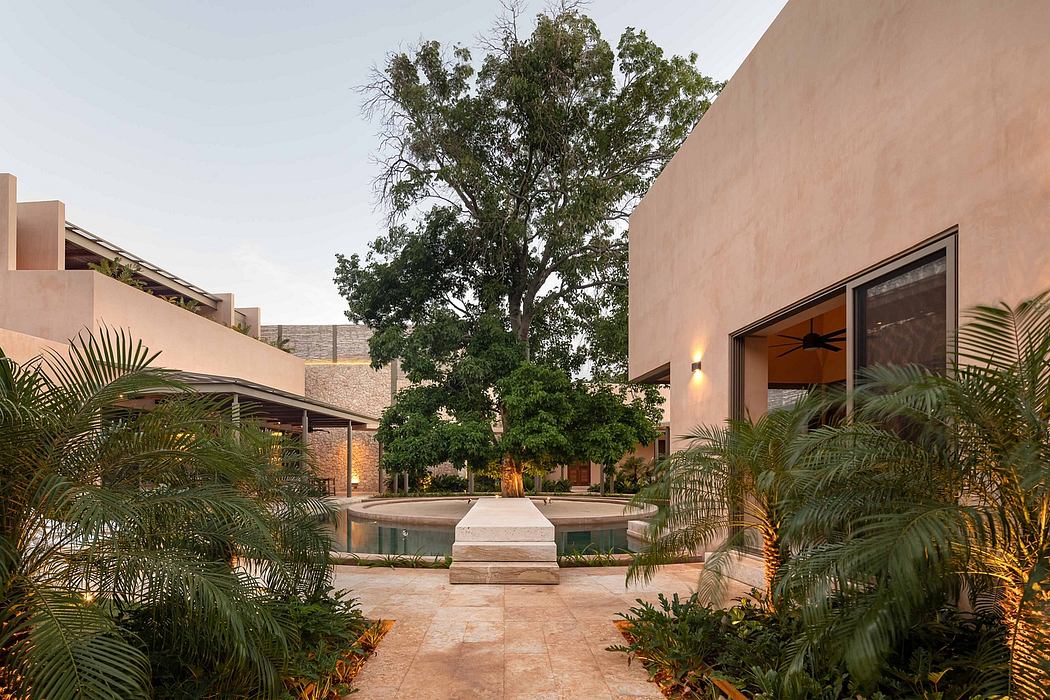 Lush tropical courtyard with a central fountain, surrounded by adobe-style buildings.