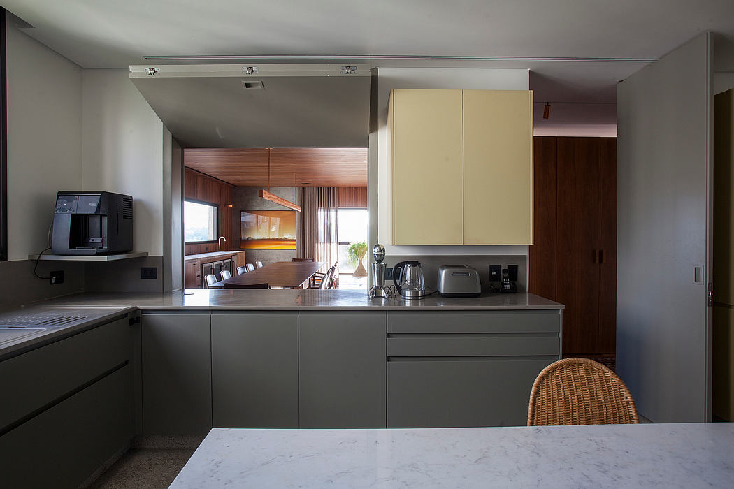 Modern kitchen interior with minimalist cabinetry, marble countertop, and natural lighting.