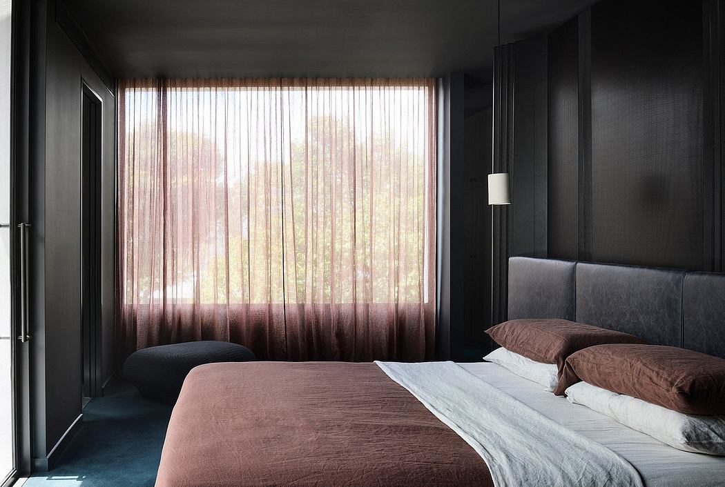 Minimalist bedroom with dark walls, large window, and muted color bedding.