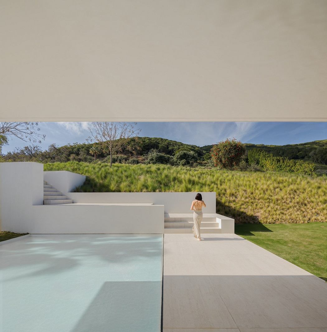 Sleek, modern architecture with a serene pool, lush greenery, and a person walking on the steps.