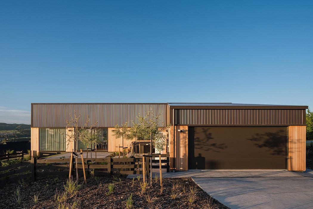 Sleek, modern wooden facade with large windows and garage doors, set against a scenic backdrop.