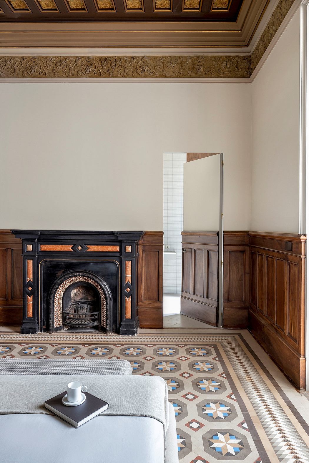 Ornate ceiling molding, intricate tile flooring, and a grand fireplace in a luxurious interior.