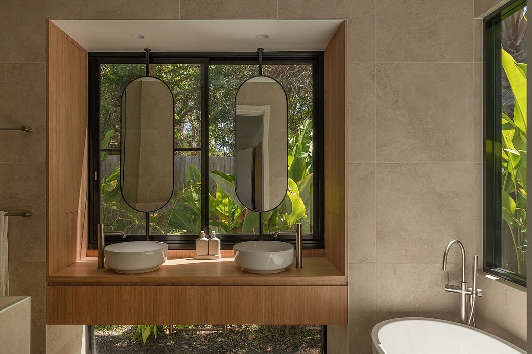 Elegant modern bathroom with large mirrored vanity, vessel sinks, and lush greenery view.