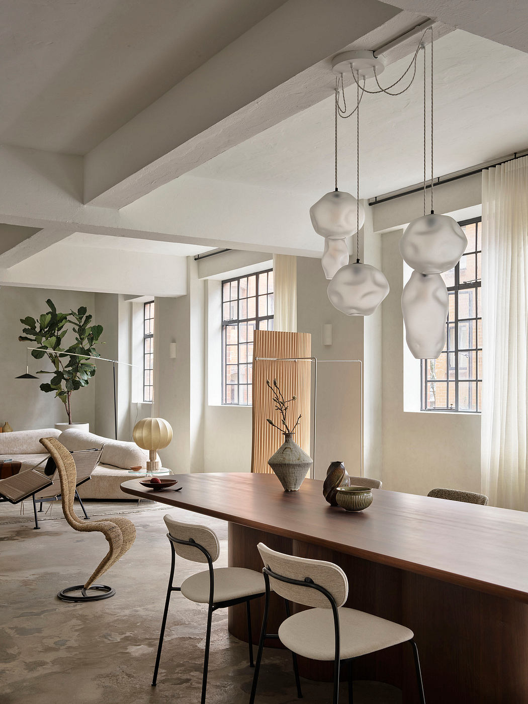 Spacious living area with large windows, modern lighting fixtures, and minimalist furnishings.