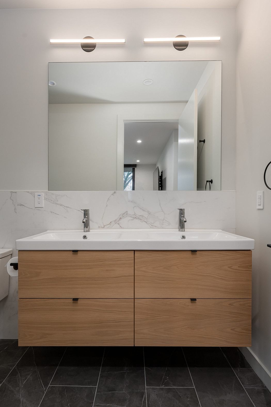 Sleek vanity with dual sinks, framed mirror, and modern lighting fixtures.