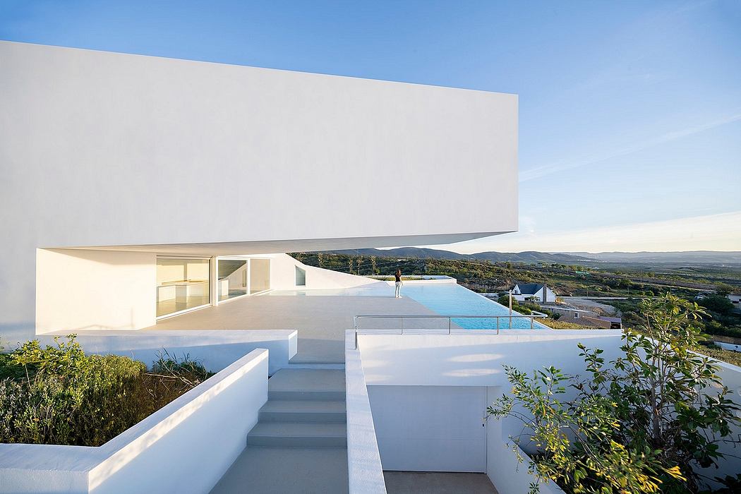 Minimalist modern villa with pool, terraces, and panoramic countryside view.