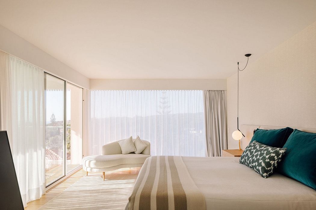 Spacious bedroom with full-length windows, soft furnishings, and minimalist decor.