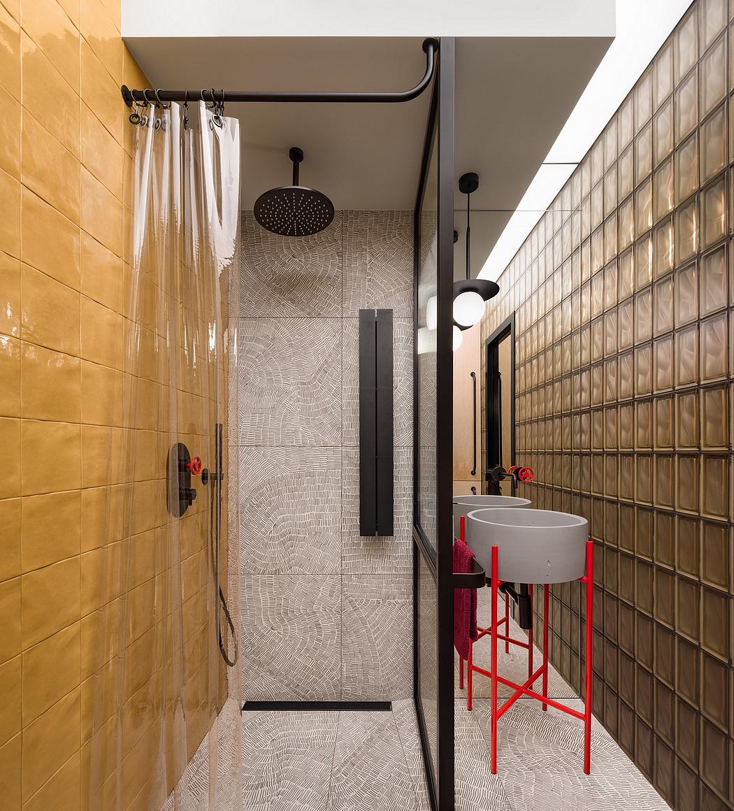 Sleek, modern bathroom with textured tiles, black fixtures, and a striking red stool.