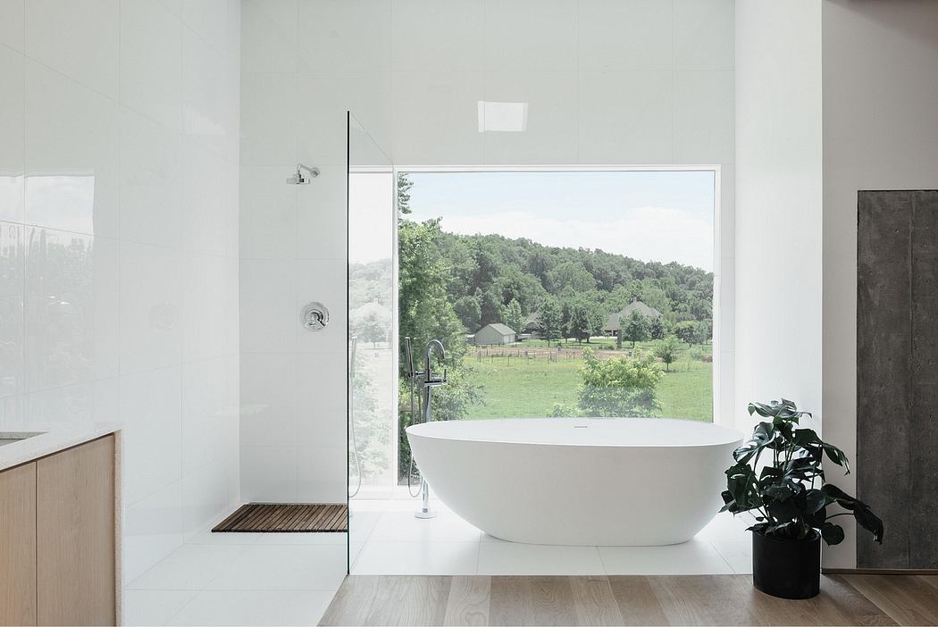 Modern, minimalist bathroom with freestanding tub, wooden accents, and scenic forest view.