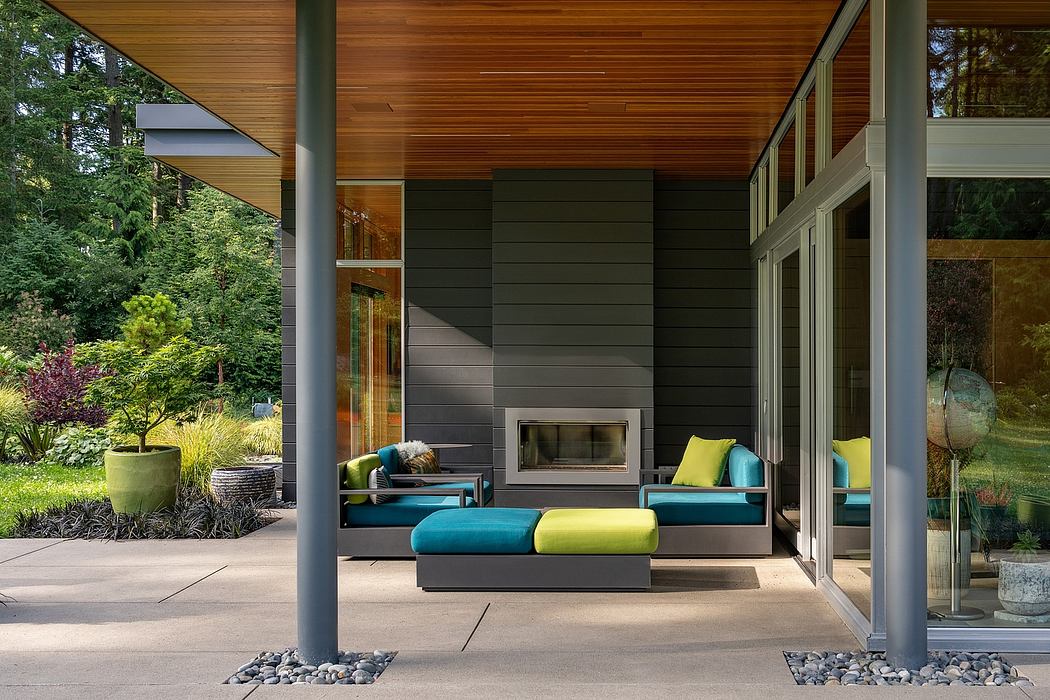 Cozy outdoor living space with modern wood-paneled architecture, plush seating, and lush greenery.