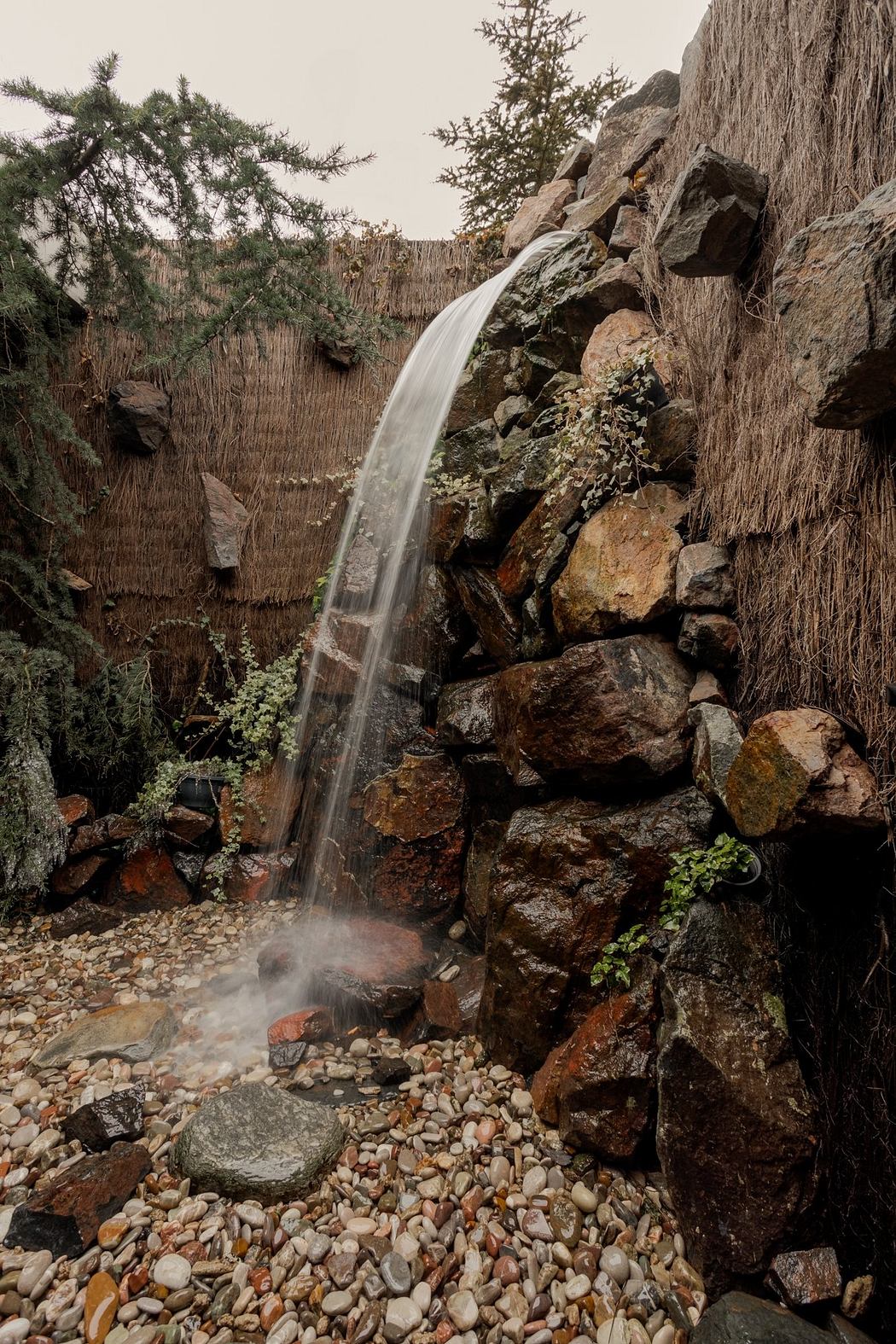 A tranquil waterfall cascades over rugged rocks, surrounded by lush foliage and a scenic landscape.
