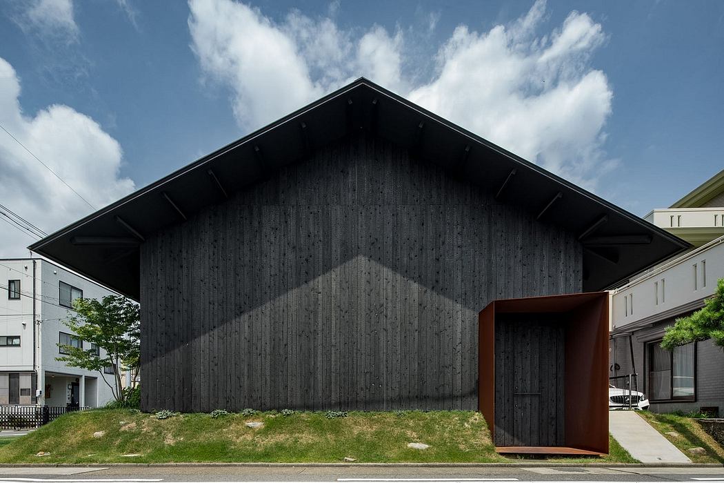 Striking black wooden facade with a prominent triangular roof and an entryway.