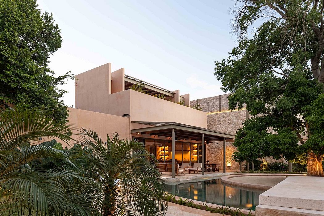 Stunning architectural design with a tranquil pool, lush greenery, and warm lighting.