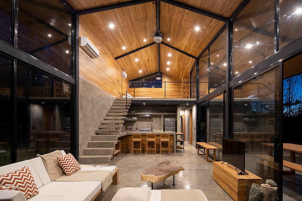 Spacious modern cabin with vaulted wood ceiling, exposed beams, and striking staircase.