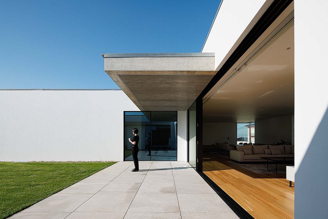 Modern concrete structure with expansive glass walls, leading to a spacious interior with hardwood floors.