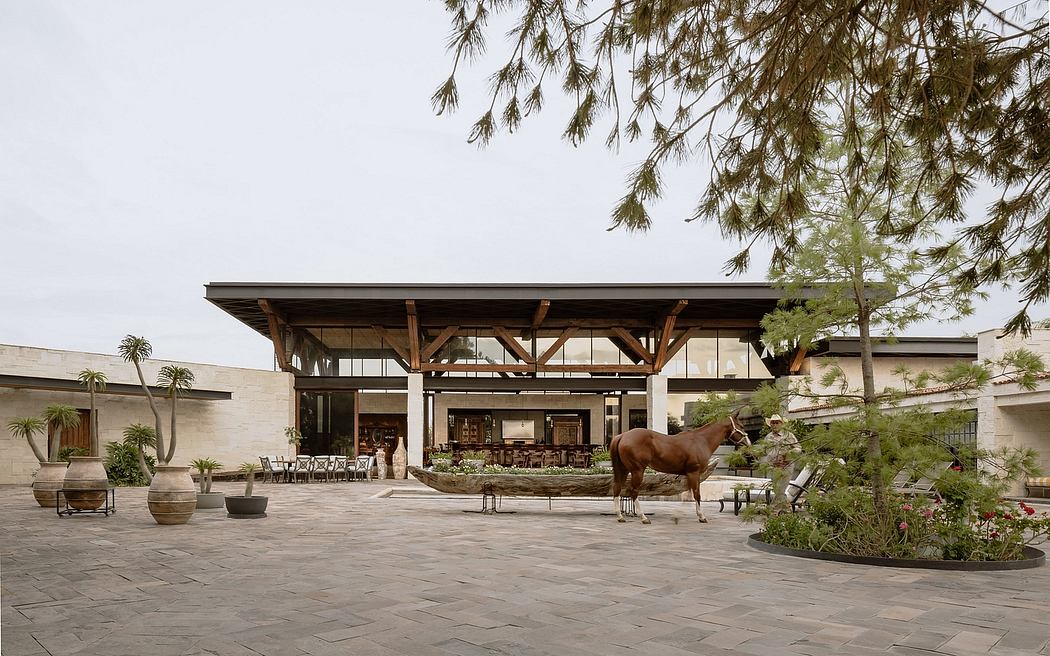 A modern resort with a spacious covered outdoor area, wooden beams, and a horse sculpture.