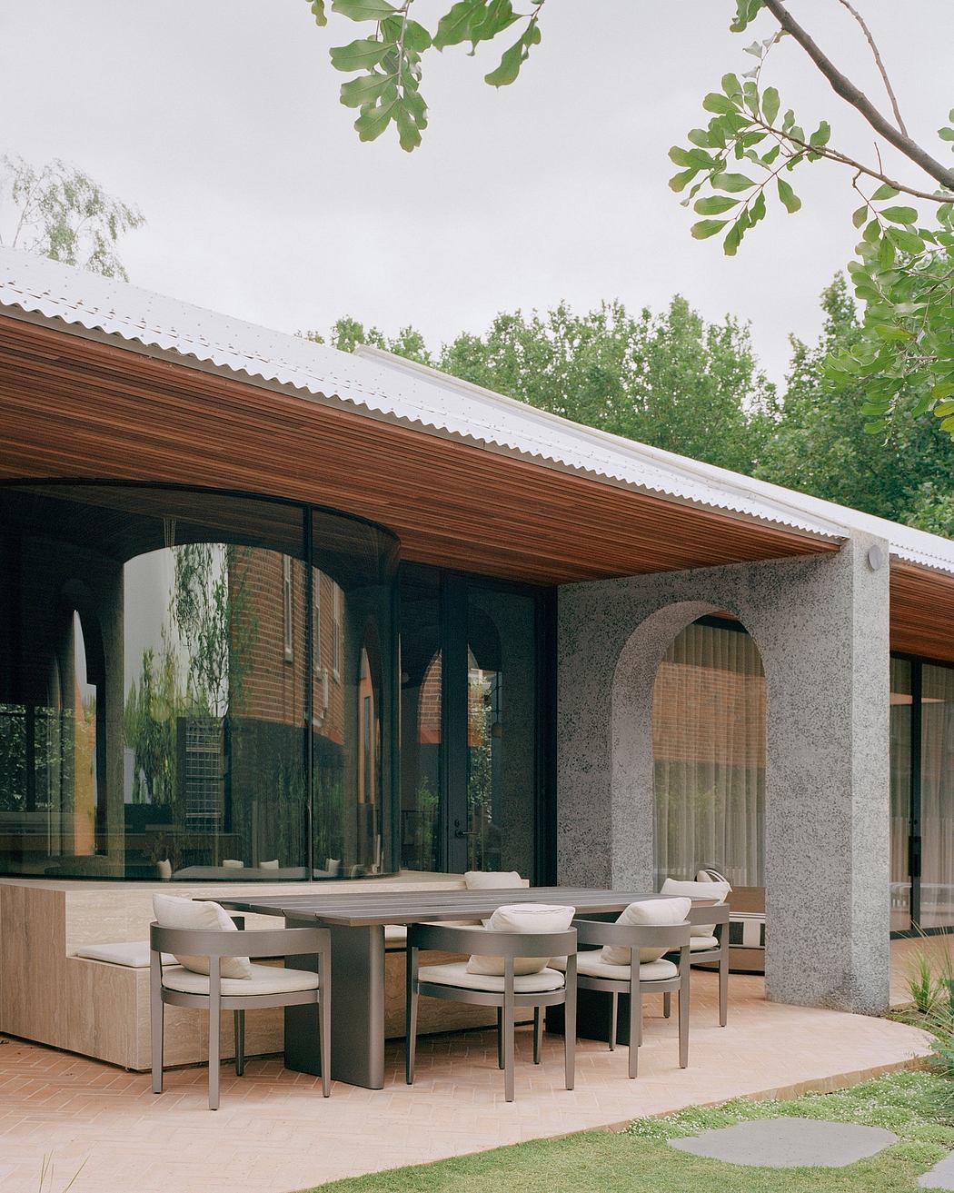 A modern home's exterior features a wooden roof, large windows, and minimalist furniture.