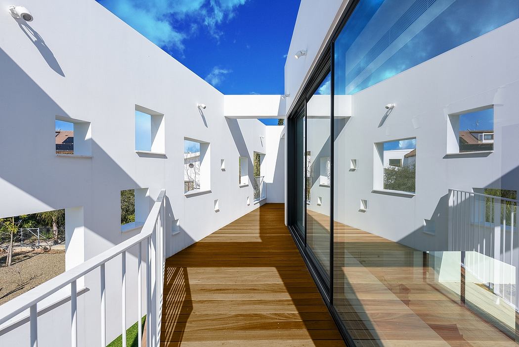 Modernist exterior with clean lines, large windows, and wooden deck against blue sky.