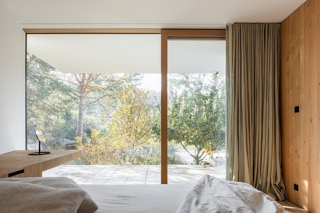 Bright modern bedroom with wooden walls, large windows overlooking a lush garden.