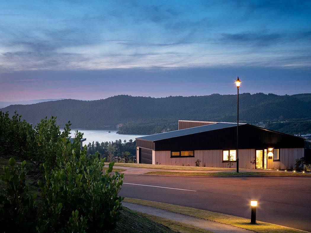 A modern building with wooden exterior and large windows overlooking a scenic landscape.
