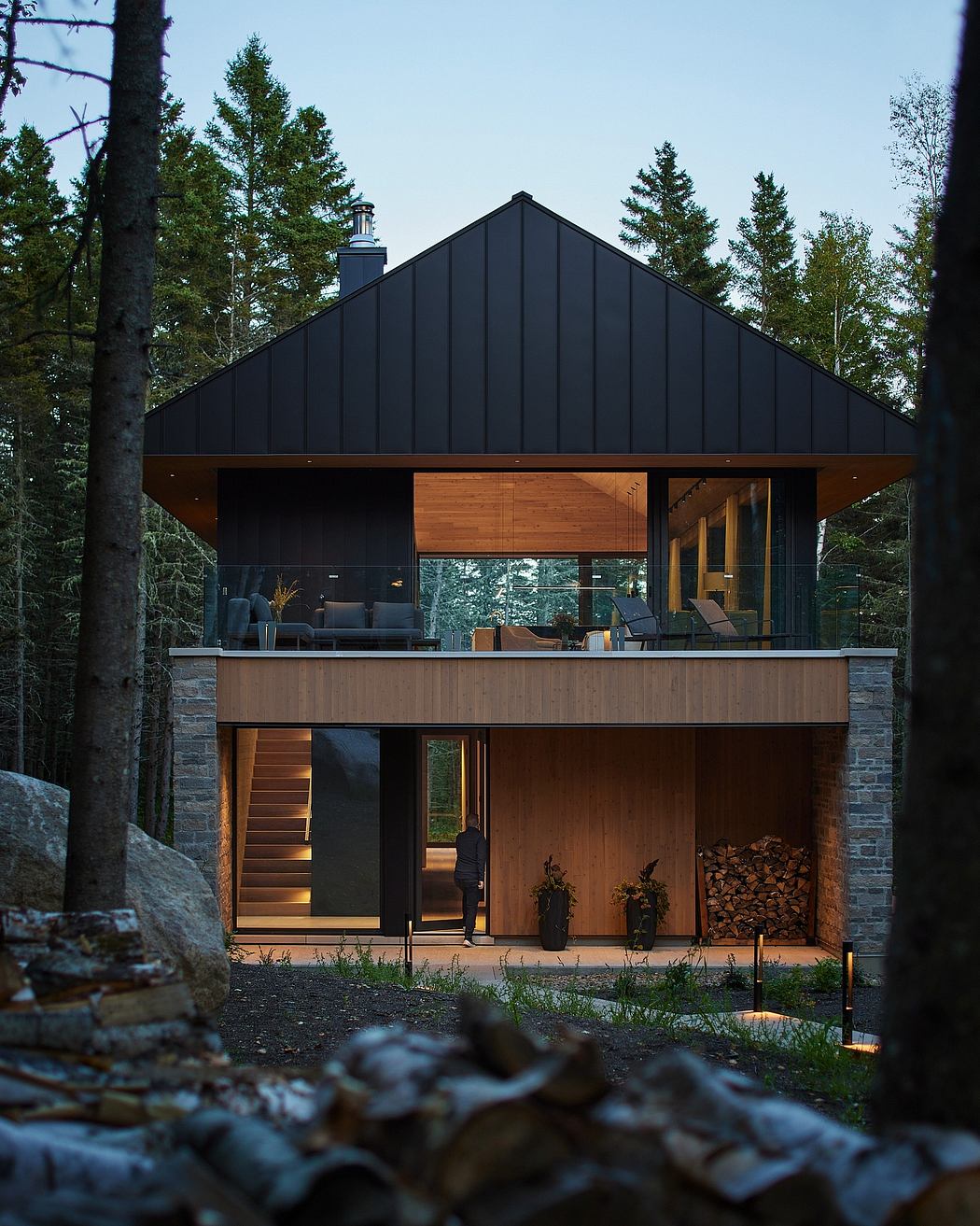 A modern, sleek cabin nestled in a forested setting, featuring a wooden exterior and large windows.