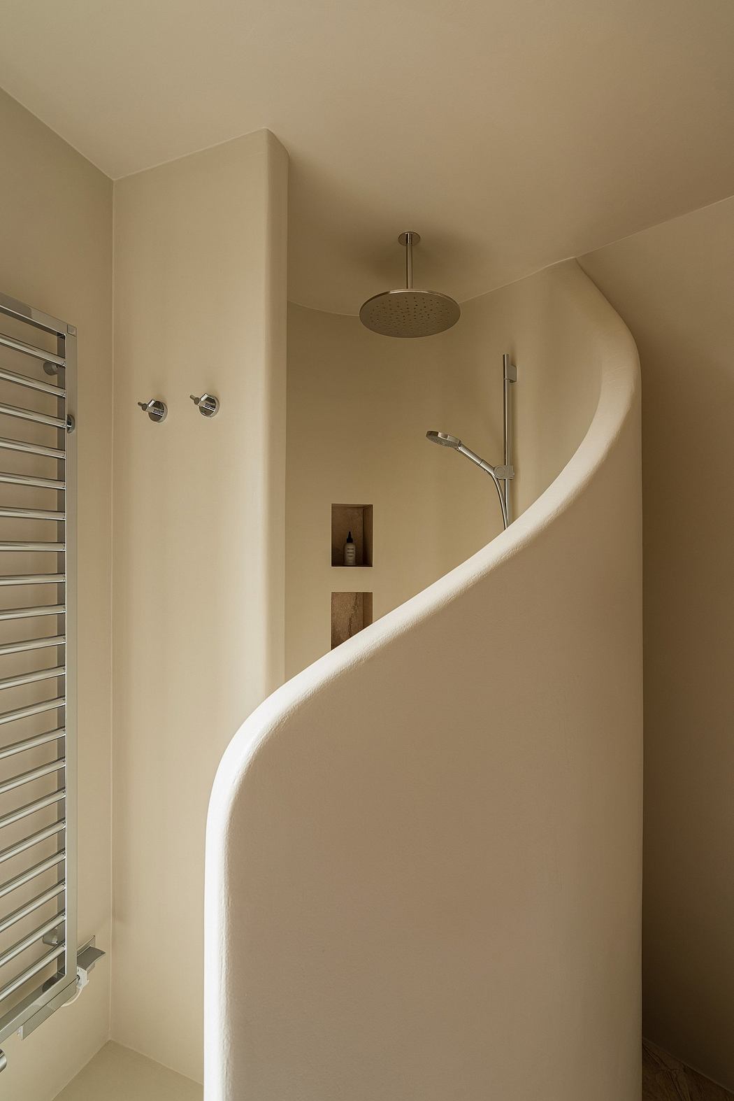 Sleek, curved shower enclosure with built-in niche and chrome fittings, creating a minimalist, spa-like ambiance.