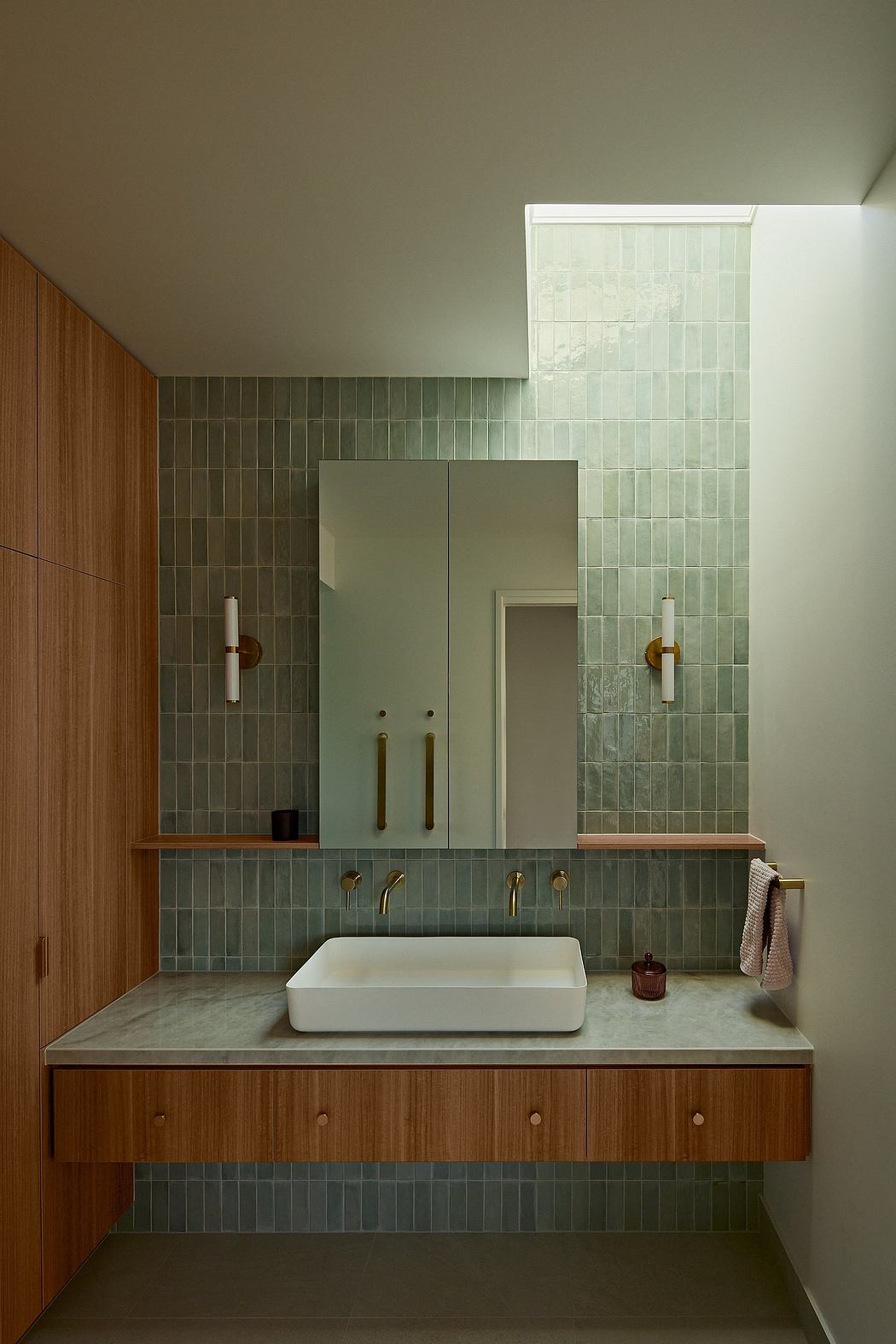 Modern bathroom interior with sleek wooden vanity, square sink, and tiled walls.