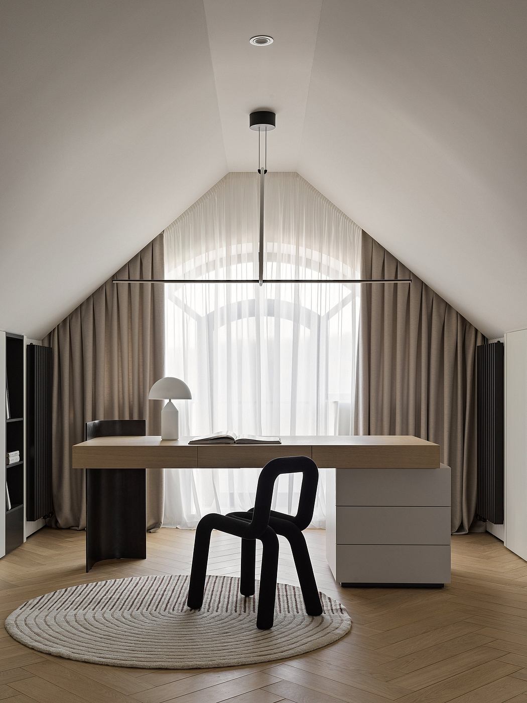 Spacious attic bedroom with modern furniture, curtained windows, and a unique black chair.