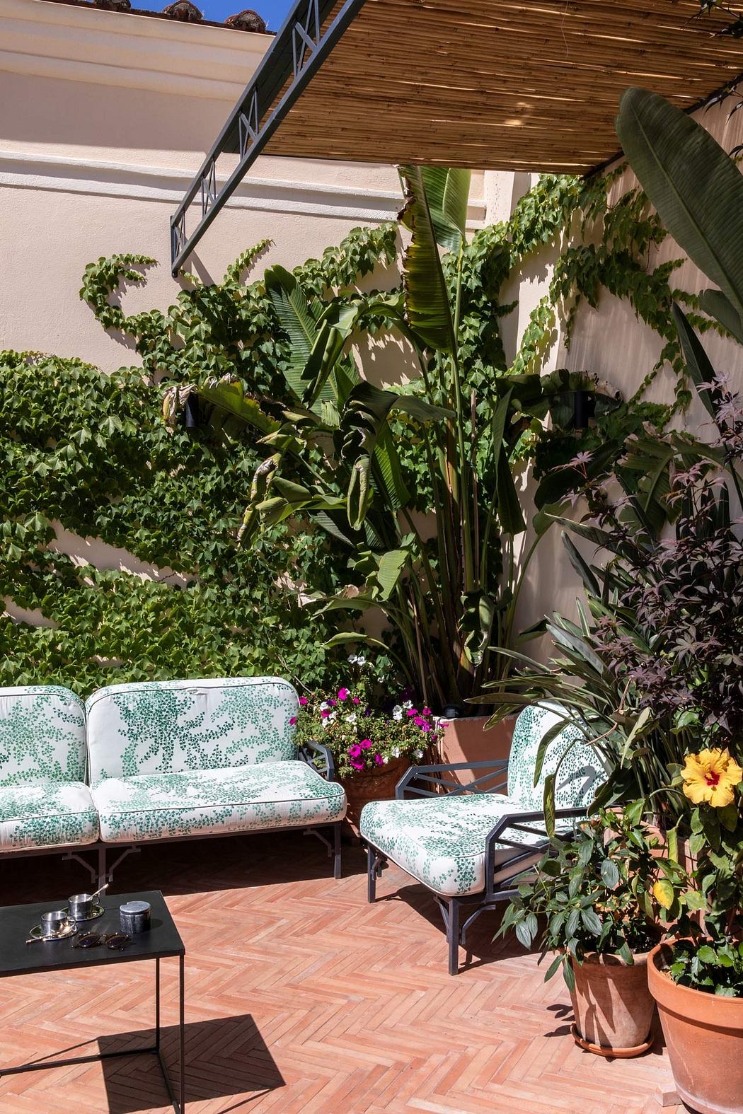 Cozy outdoor patio with woven seats, potted plants, and a wooden pergola overhead.