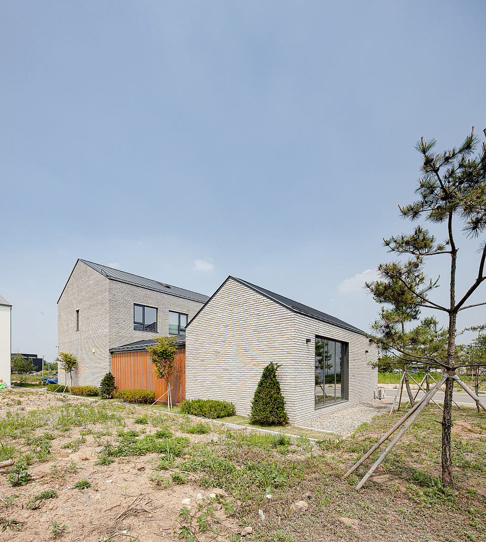 Contemporary residential building with pitched roof, brick facade, and large windows.