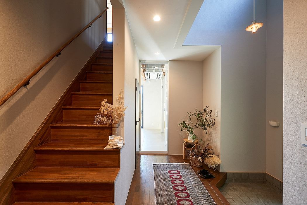 Welcoming foyer with wooden stairs, decorative alcove, and patterned rug.