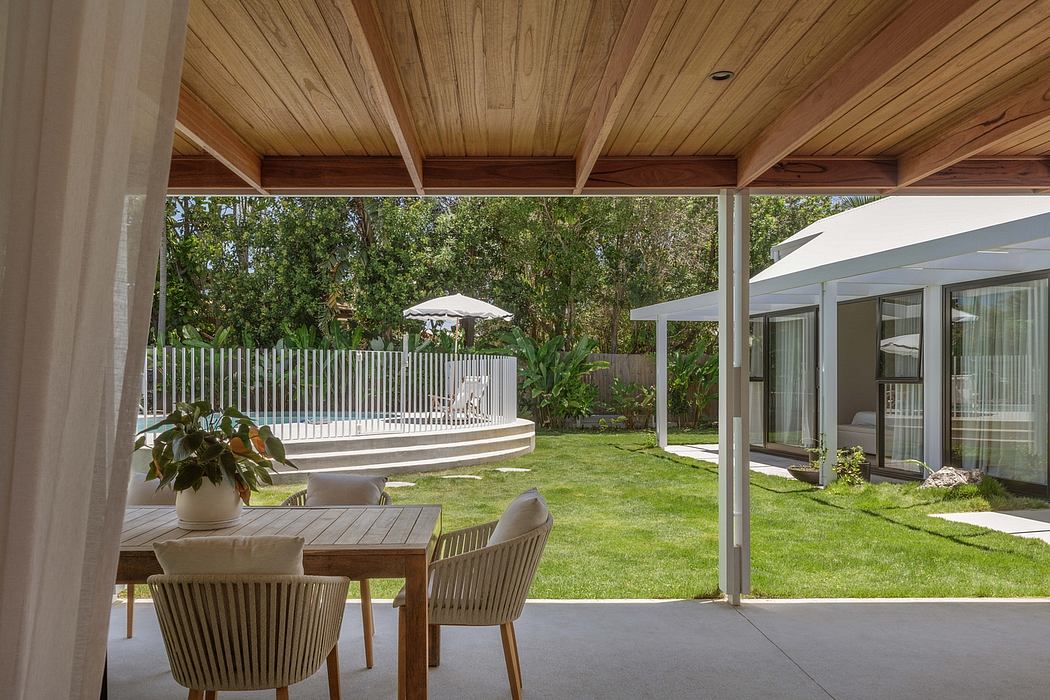 Cozy outdoor living area with wooden ceiling, lush greenery, and inviting patio furniture.