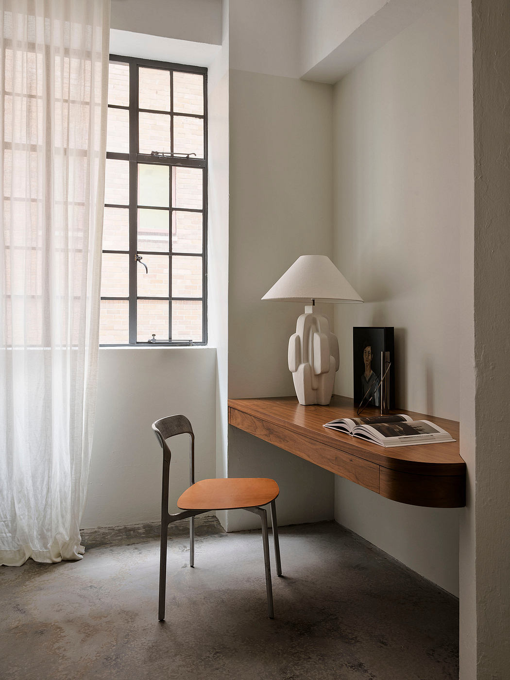 A cozy home workspace with a wooden desk, modern lamp, and minimal decor.