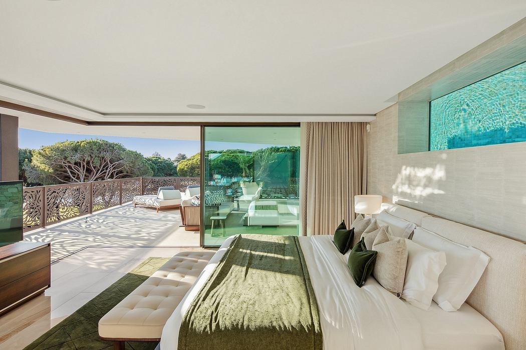 Spacious, modern bedroom with large windows overlooking lush outdoor greenery.