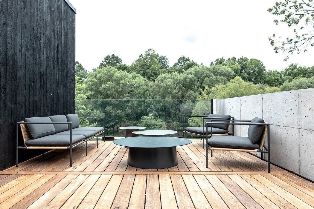 Sleek, modern outdoor space with wooden deck, concrete walls, and minimalist furniture.