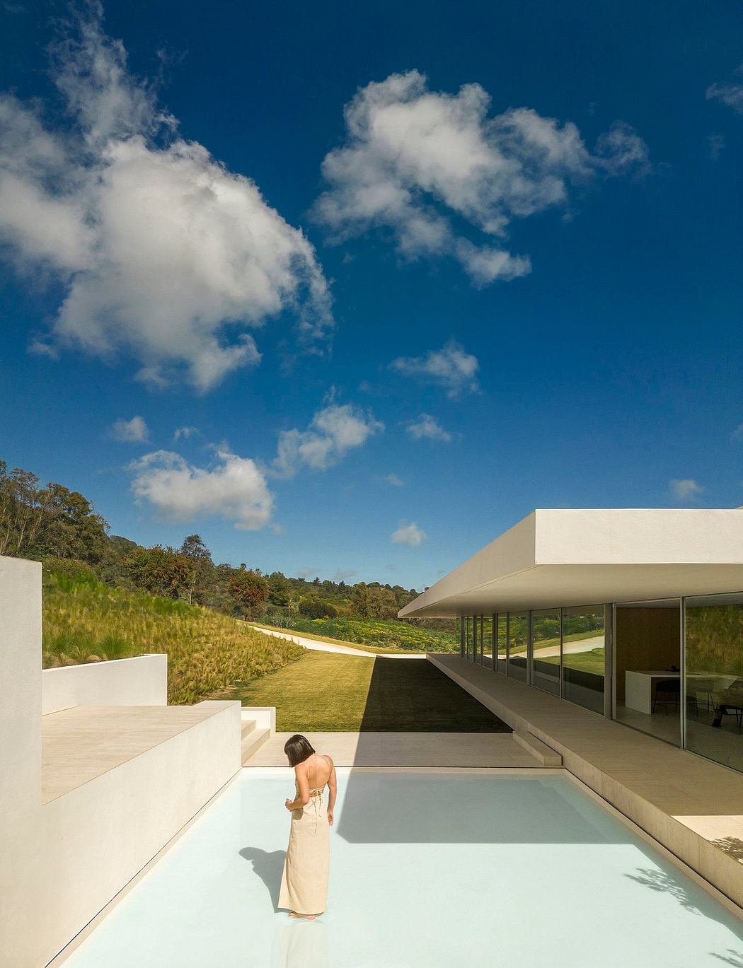 Minimalist modern architecture with clean lines, glass facade, and lush outdoor landscape.