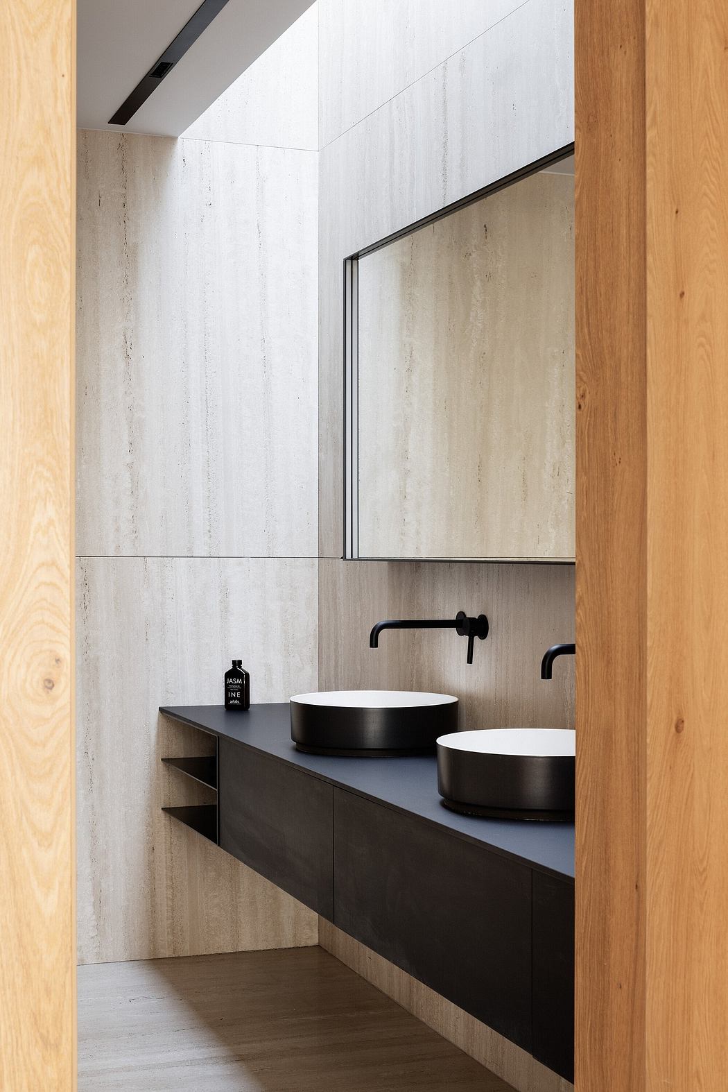 Modern bathroom vanity with black countertop, vessel sinks, and wood-paneled walls.