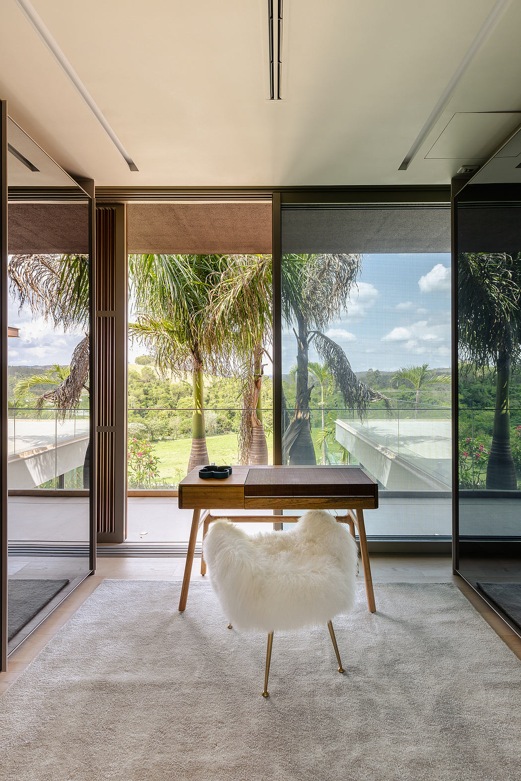 A modern, minimalist workspace with lush tropical views through floor-to-ceiling windows.