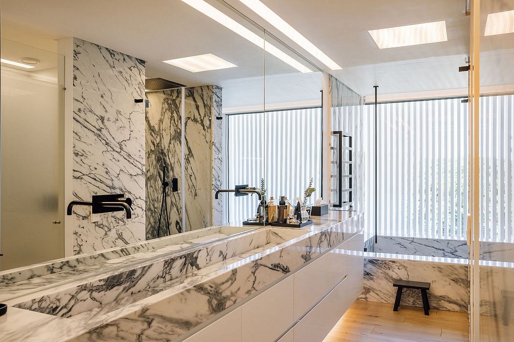 Sleek modern bathroom with floor-to-ceiling marble tiles, sinks, and large mirrored vanity.