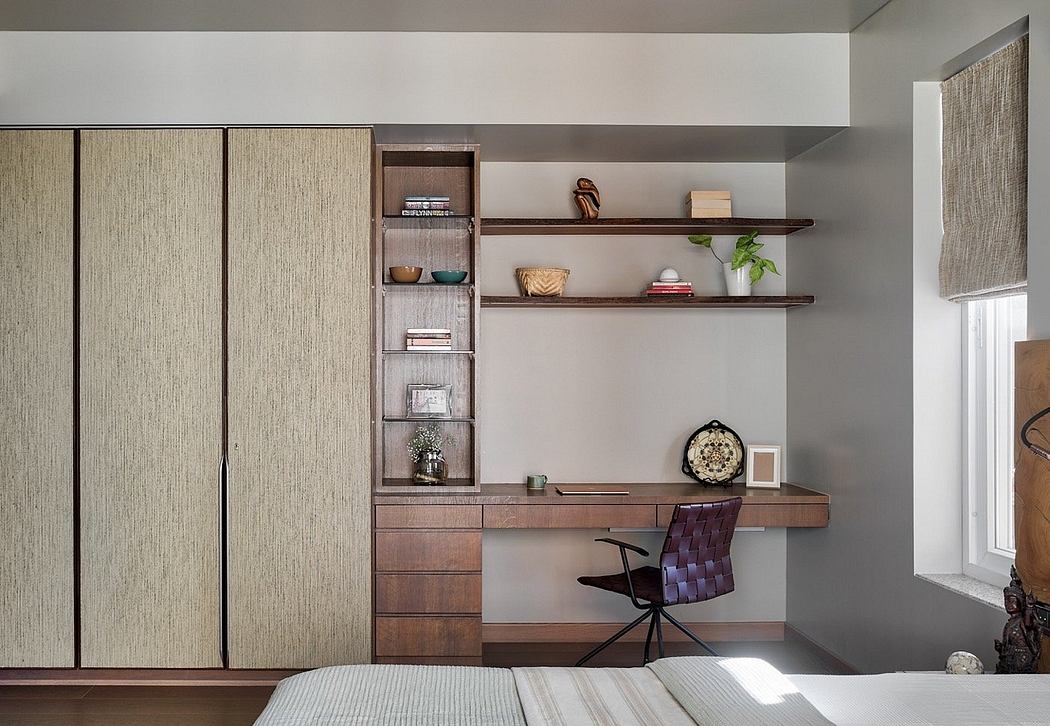 A modern bedroom with built-in storage, shelves, and a wooden desk integrated into the design.