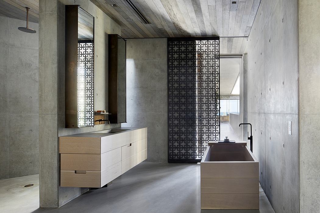 Minimalist bathroom with concrete walls, wood vanity, and geometric metal partition.